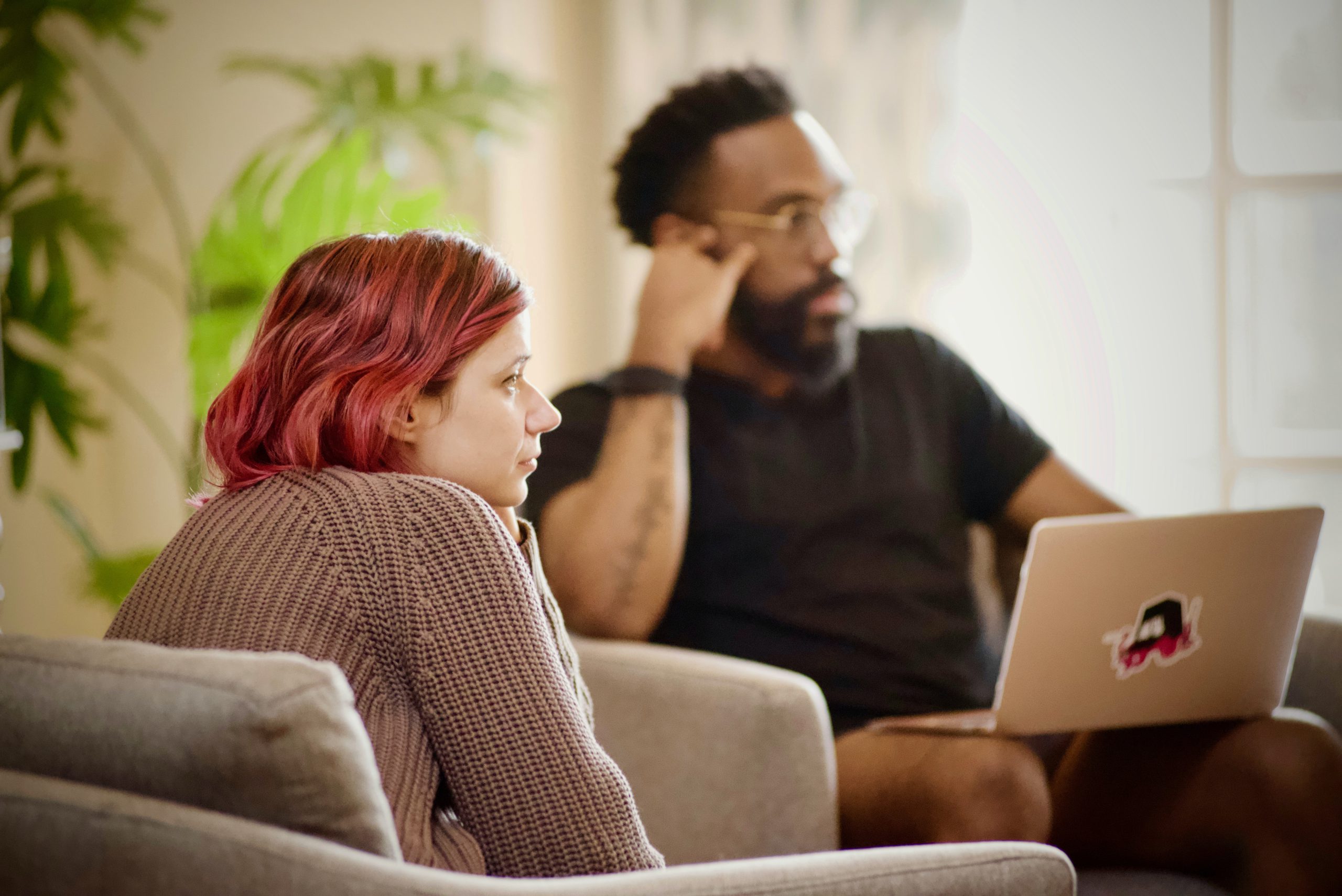 a red-haired woman and a man listen attentively during a team meeting.
