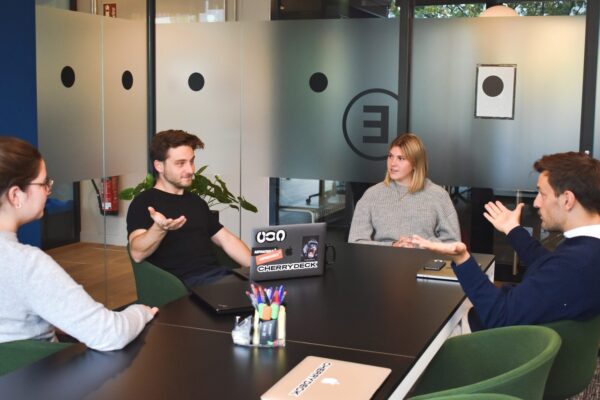 a group of 2 women and 2 men who are work colleagues and who talk to each other on the premises of their company during a meeting to find solutions to their problem.