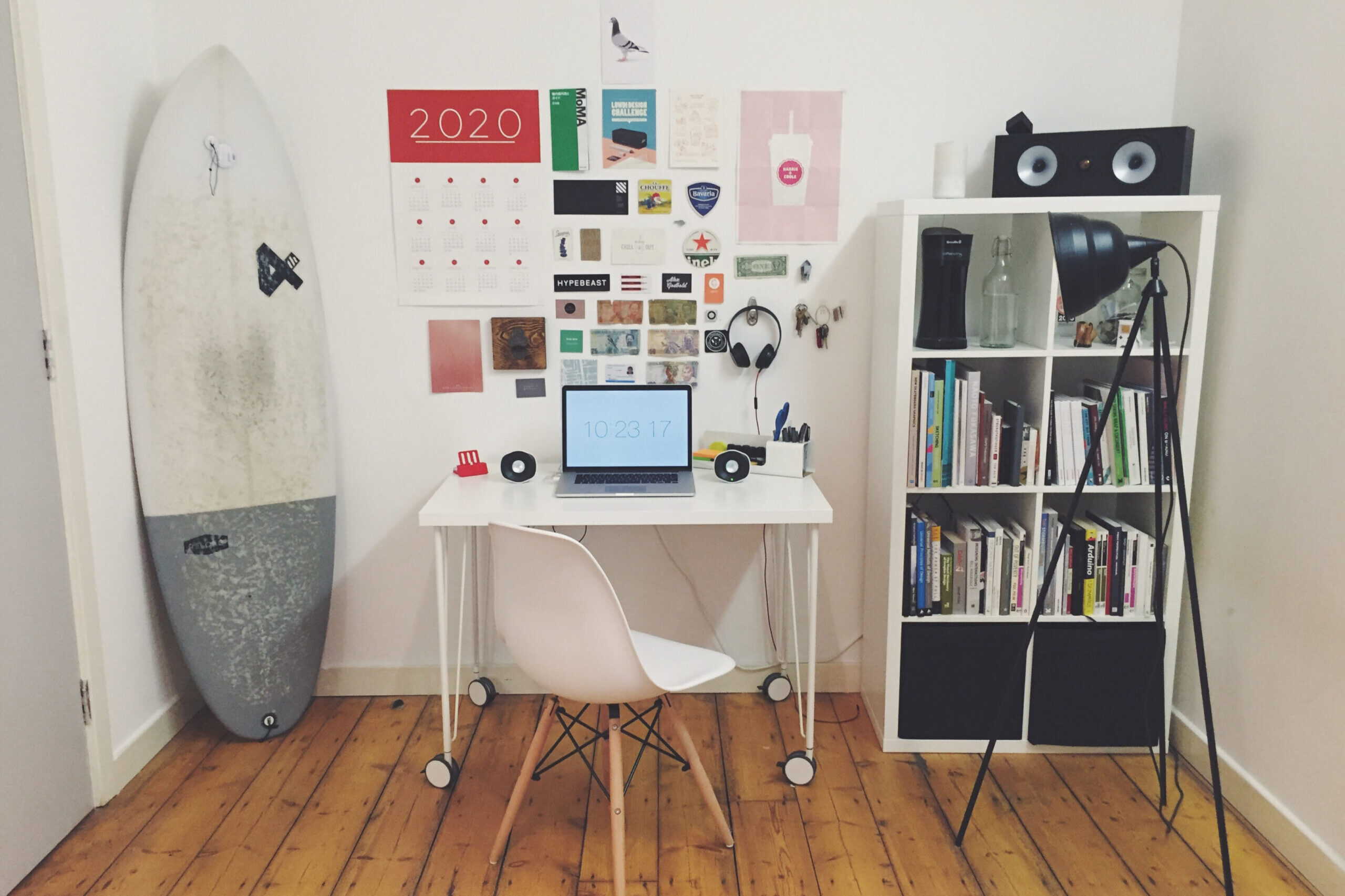 Simple and cosy home-office with surf-board, bookshelf and small desk with laptop